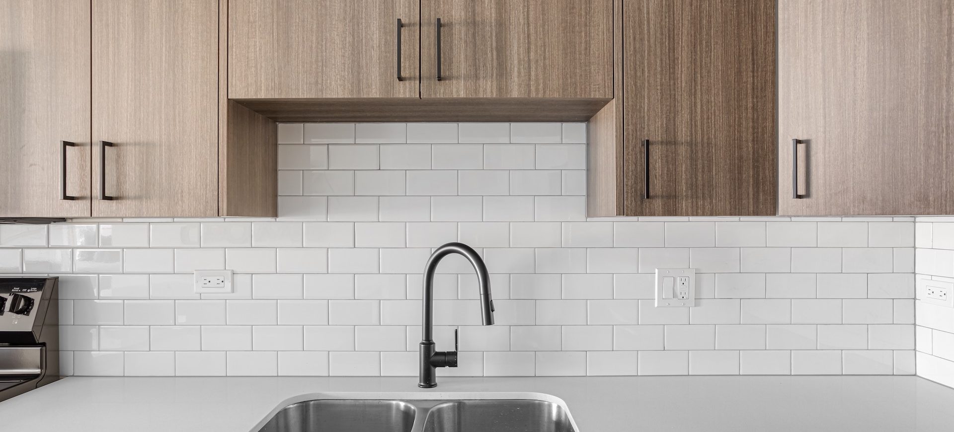 Modern kitchen sink with contemporary faucet and light wood cabinetry at Station 250 apartment interiors Mundelein