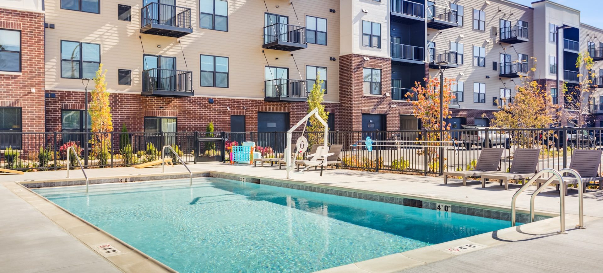 Outdoor swimming pool with bright blue water and concrete deck surrounded by Station 250 apartment buildings with private balconies in Mundelein IL