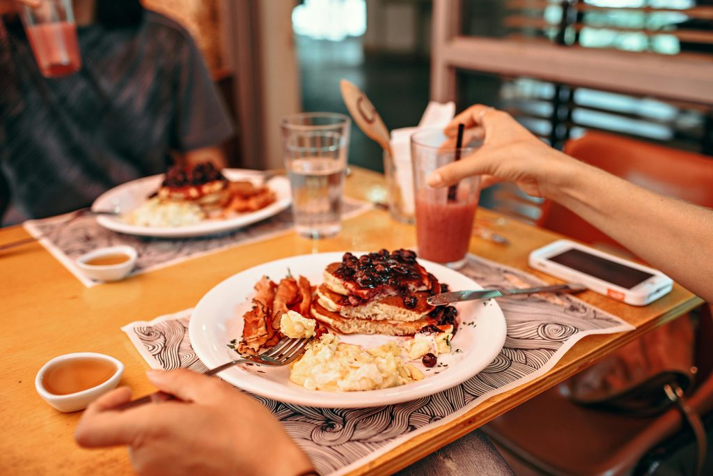 Two people sitting at table eating breakfast