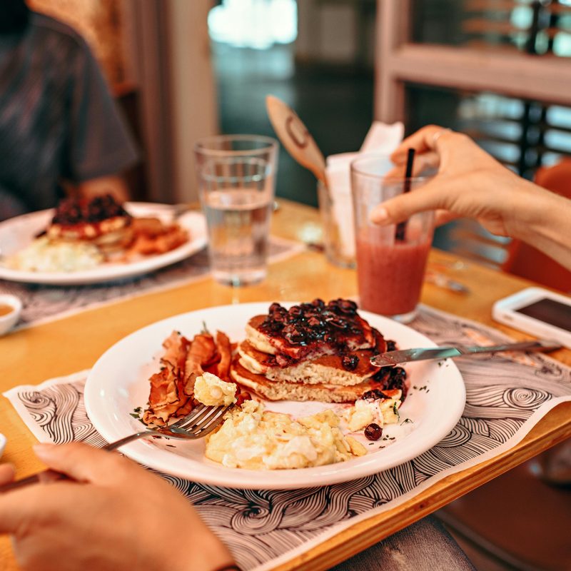 Two people sitting at table eating breakfast