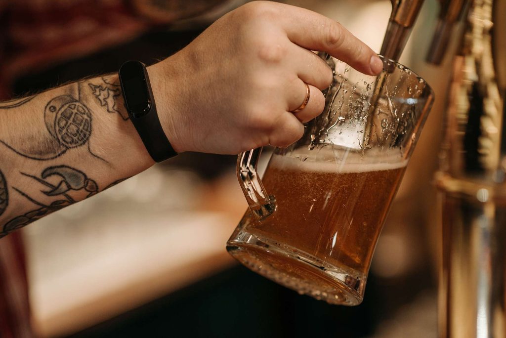 Closeup of hand filling up beer with tap