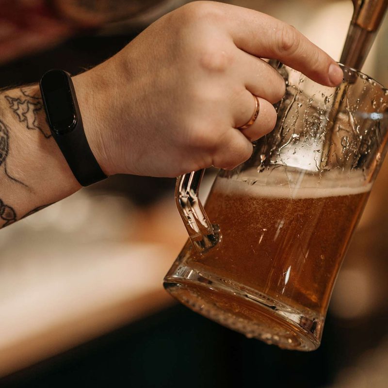 Closeup of hand filling up beer with tap